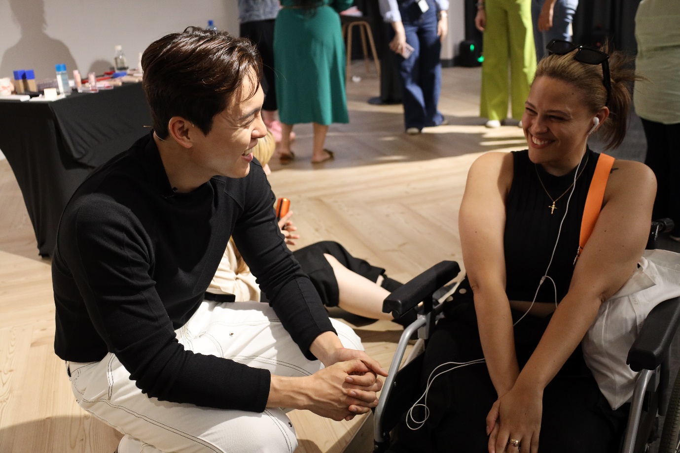 A person and person sitting on a wood floor

Description automatically generated