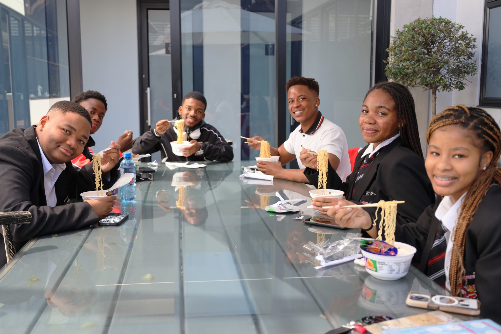 A group of people eating noodles at a table

Description automatically generated