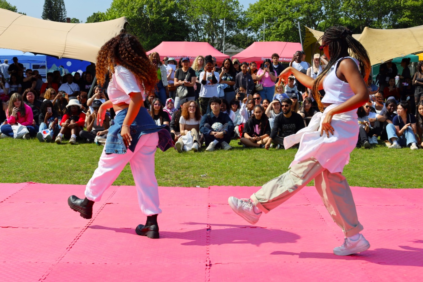 A group of women dancing on a pink mat

Description automatically generated