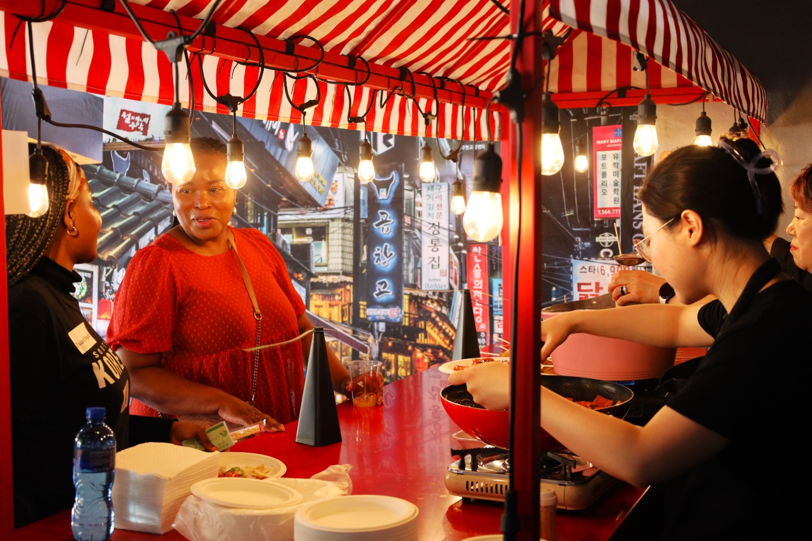 A person standing behind a counter with a red and white striped tent

Description automatically generated