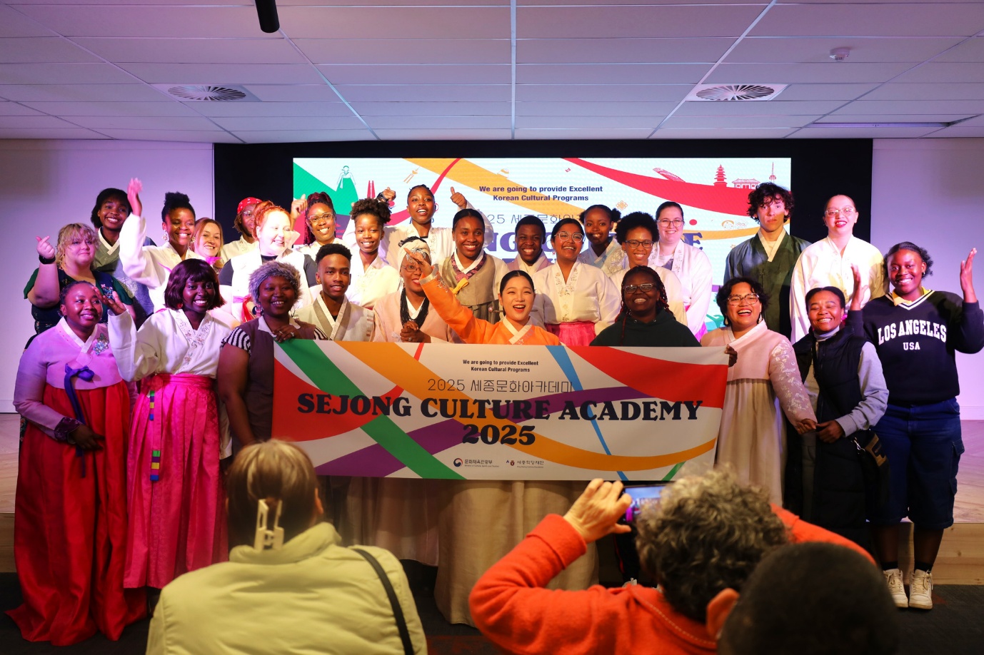 A group of people standing in front of a large banner
AI-generated content may be incorrect.