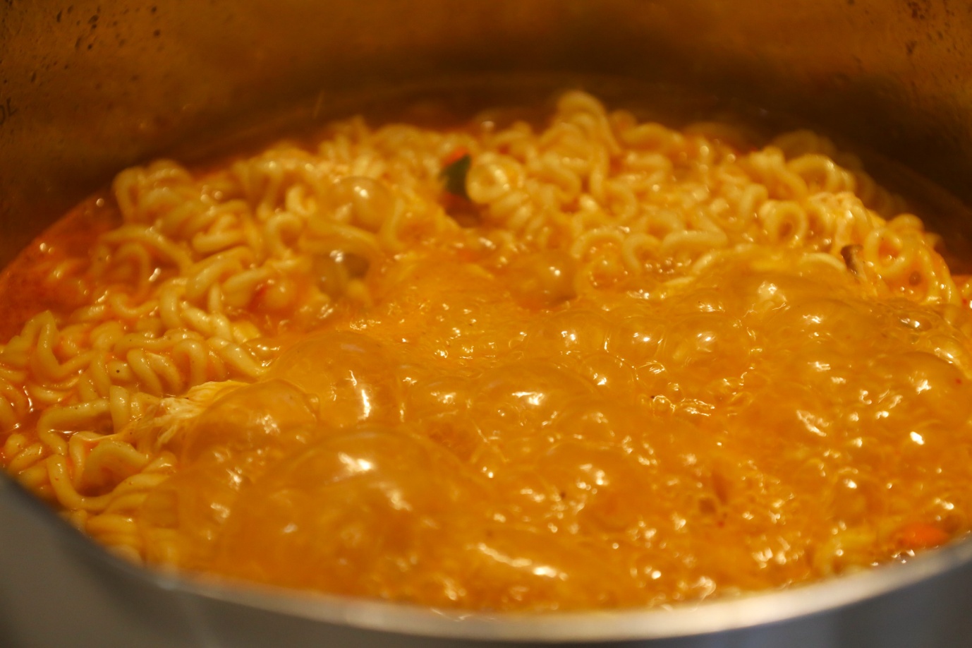 A pot of noodles with orange liquid
AI-generated content may be incorrect.