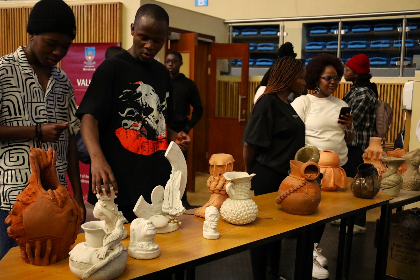 A group of people standing next to a table with pottery
AI-generated content may be incorrect.