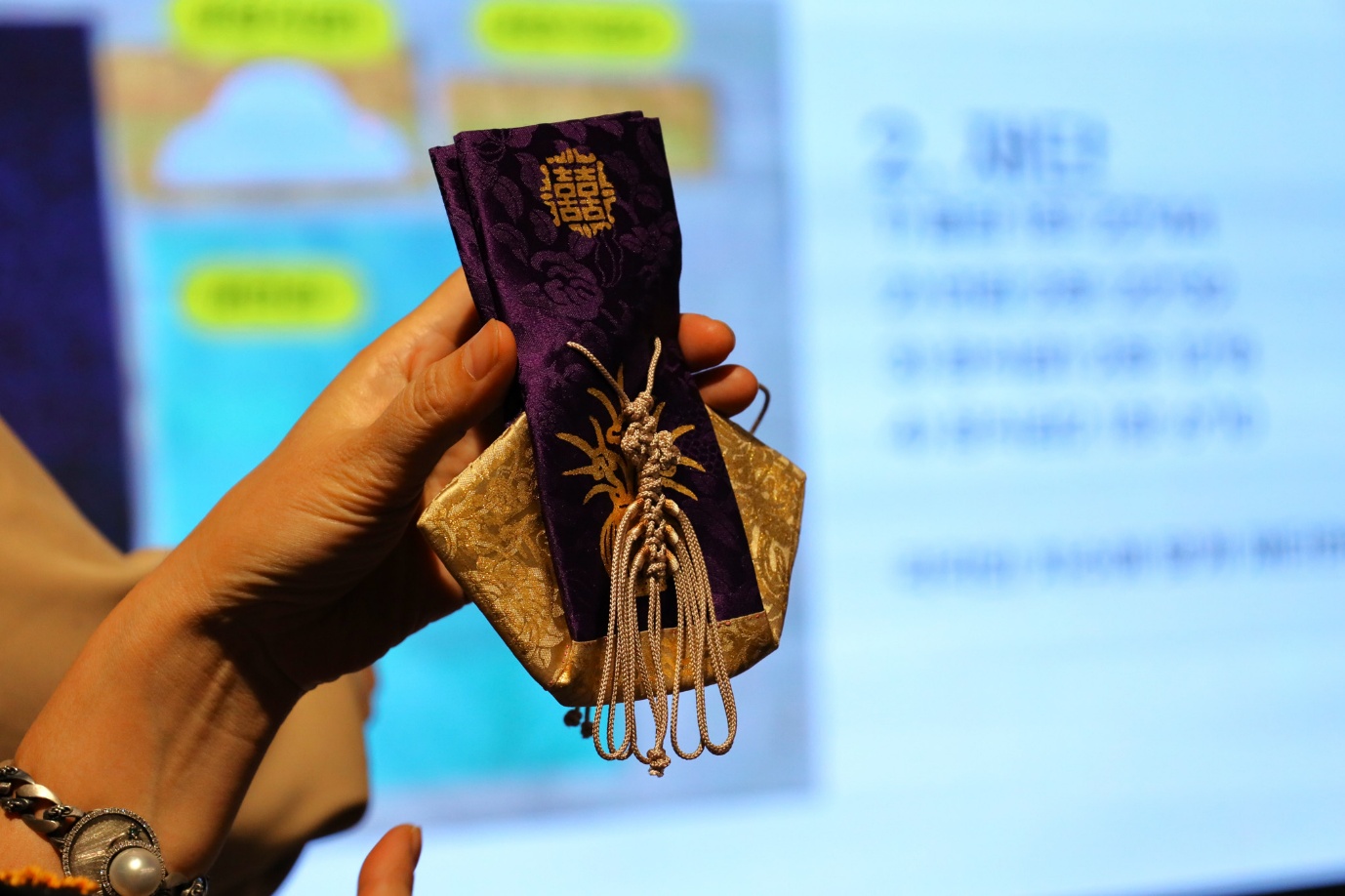 A hand holding a purple and gold fabric
AI-generated content may be incorrect.