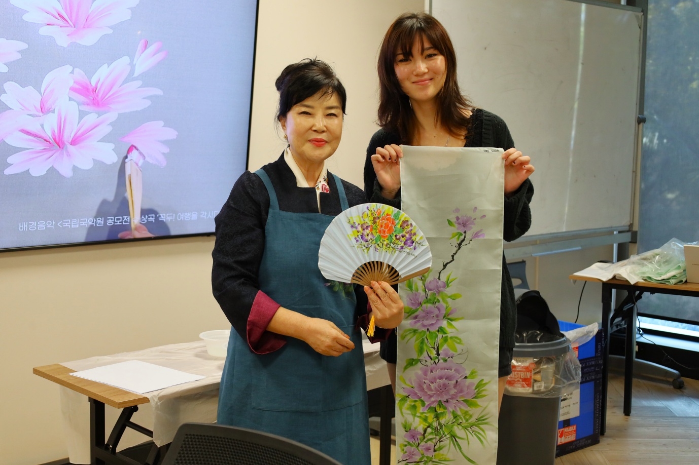 A couple of women holding a fan and a paper
AI-generated content may be incorrect.