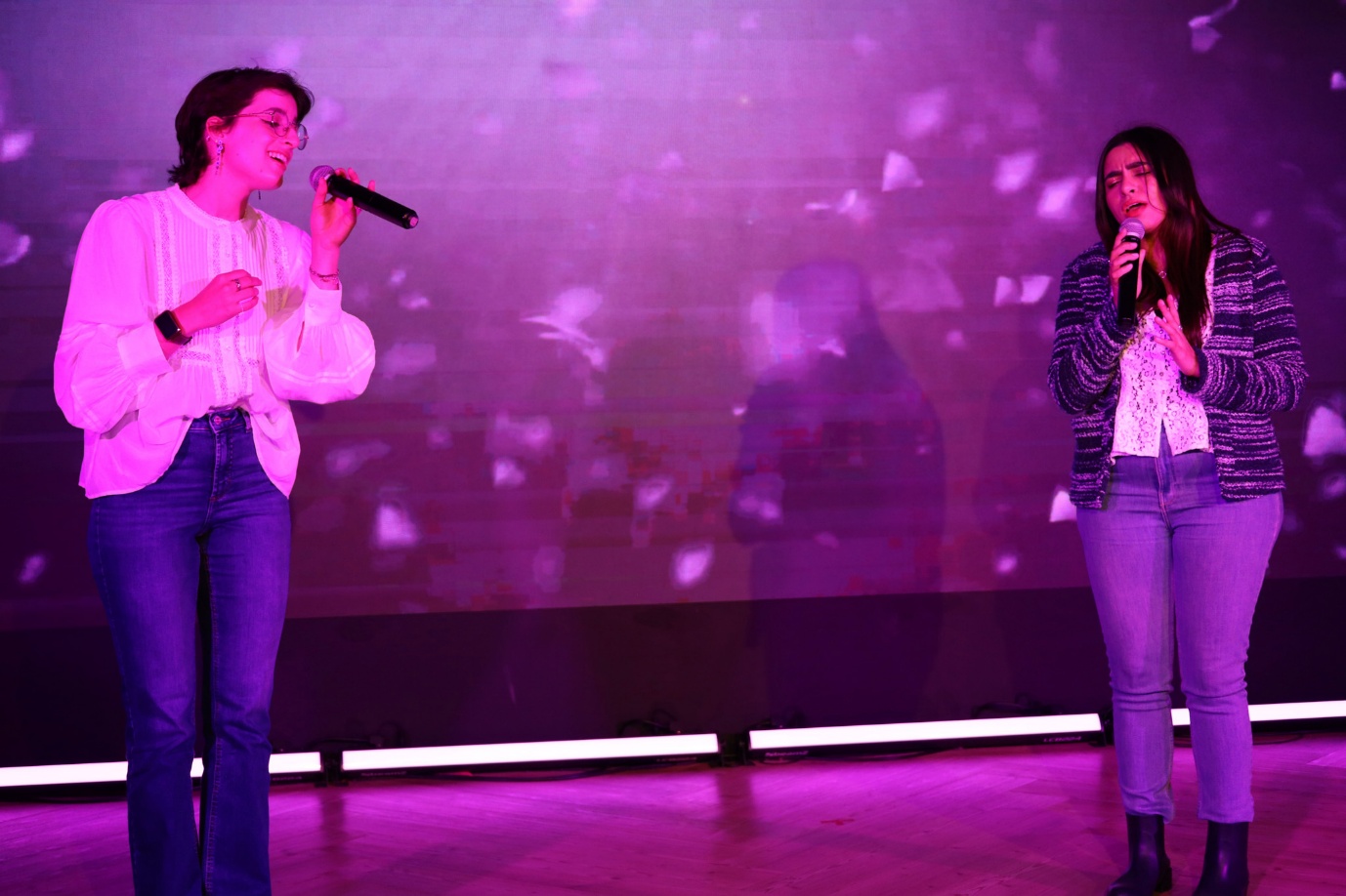A couple of women singing on stage

AI-generated content may be incorrect.